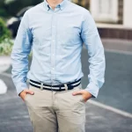 handsome-young-businessman-sunglasses-walking-street-he-holds-hands-pockets